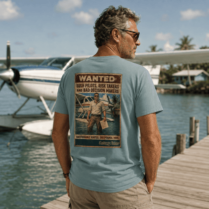 Man wearing an embargo aviation theme t-shirt, standing on a dock with a seaplane in the background.