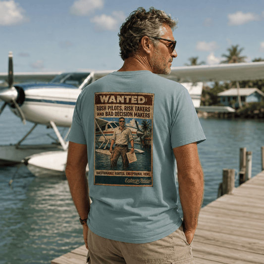 Man wearing an embargo aviation theme t-shirt, standing on a dock with a seaplane in the background.