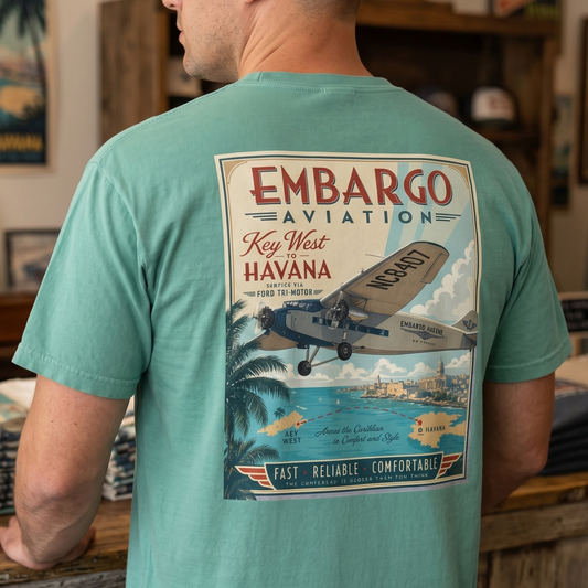 Person wearing a teal t-shirt with 'Embargo Aviation' graphic in a store setting.